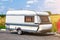 A motor home in the form of a white trailer in a parking lot near the road, secured to the car while traveling in remote