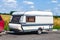 A motor home in the form of a white trailer in a parking lot near the road, secured to the car while traveling in remote