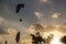 Motor paraplan flies in the sky between the clouds in the setting sun