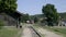 Motor passenger train arrives at train station. Red locomotive runs on narrow-gauge track