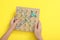 Motor skills development. Boy with geoboard and rubber bands at yellow table, top view