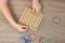 Motor skills development. Girl playing with geoboard and rubber bands at wooden table, top view