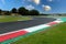 Motor sport circuit asphalt track curb close up on straight and green field