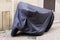 Motorbike cover plastic protected in street motorcycle with dark tarpaulin jacket