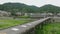 Motorbike crosses narrow bridge with no railing in small rural town