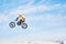 Motorbike, jump and man in the air with blue sky, mock up and stunt in sports with fearless person in danger with