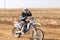 Motorbike kicking up trail of dust on sand track during rally ra