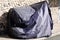 Motorbike protected by dark grey blue protective cover tarpaulin jacket bike in street