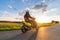 Motorbiker riding on empty road with sunset sky