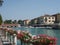 Motorboats parked along the peschiera del garda canal in lake garda, italy  with local businesses in the background and flowers at