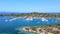 Motorboats and sailboats anchored in harbor with amazing blue sea on sunny summer day. Aerial view