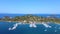 Motorboats and sailboats anchored in harbor with amazing blue sea on sunny summer day. Aerial view