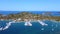 Motorboats and sailboats anchored in harbor with amazing blue sea on sunny summer day. Aerial view