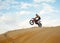 Motorcross riding over sand in desert dune