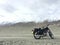 Motorcycle alone enduro traveler with suitcases standing on rocky plateau in cloudy weather on the background.