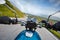 Motorcycle driver riding in Alpine highway, handlebars view, Dolomites, Europe.