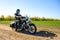 Motorcycle Driver Riding Custom Chopper Bike on Autumn Dirt Road in the Green Field. Adventure Concept.