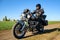 Motorcycle Driver Riding Custom Chopper Bike on Autumn Dirt Road in the Green Field. Adventure Concept.