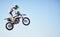 Motorcycle, jump and person on blue sky mockup for training, competition or challenge with safety gear. Professional