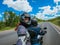 Motorcycle passenger young woman in a helmet makes selfie on action camera while riding on back of motorcycle on an empty