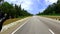 Motorcycle ridding from flat angle at tarmac road with lush green forests