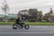 A motorcycle rides on the street at high speed. The motorcyclist is dressed in black clothes. Motion blur