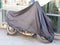 Motorcycle in street protected by protective cover tarpaulin jacket