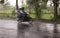 Motorcycle with two riders sweep by during heavy rain in Java, Indonesia