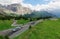 Motorcycles and cars traveling through a sharp turn of a highway winding at the foothills of rugged Sella