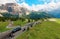 Motorcycles and cars traveling through a sharp turn of a highway winding at the foothills of rugged Sella