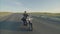 Motorcyclist in black vest and helmet rides motorcycle on highway in the steppe, front view. Biker rides along road on
