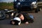 A motorcyclist lies on the asphalt near a motorcycle and car