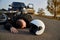 A motorcyclist lies on the asphalt near a motorcycle and car