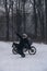 Motorcyclist man dancing with happiness near adventure motorcycle. Winter snow fall. off road dual sport crazy extreme ride,