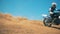 Motorcyclist is performing a trick while driving a motorbike through dust