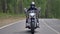 A motorcyclist rides a country road and grips both handlebars.