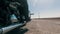 A motorcyclist rides a motochopper on a vacant lot, on a straight road. Reflection of hills on the exhaust pipe, close