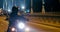 Motorcyclist Rides Motorbike on Bridge in big City Downtown at night in Warsaw