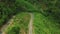 Motorcyclist riding a bike across curvy road in the mountain with lush greenery.