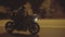 Motorcyclist riding fast on powerful sport motorbike at night road. Male racer in protective moto equipment moving on