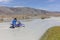 A motorcyclist takes a motorcycle through a white mountain river, his friend helps him. Mongolia, Altai