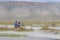 A motorcyclist takes a motorcycle through a white mountain river, his friend helps him. Mongolia, Altai