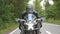 Motorcyclist travel at motorcycle on forest country road. Man in helmet rides on modern sport motorbike at woodland