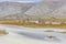 A motorcyclist is waiting for his friend to help transport motorbikes across a mountain river, Altai Mongolia