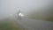Motorcyclists ride slowly on a road in the fog