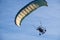 Motorized paraglider flying in blue sky