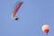 Motorized paraglider and hot air balloon against a beautiful blue sky