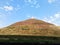 A mound of burnt yellow grass on a blue sky background and white clouds of the air. Hiking, Cycling or horse riding. climbing