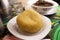 A mound of yellow Garri or Eba placed on a white plate