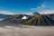 Mount Bromo, East Java, Indonesia. Clouds cover the valley floor. White gas rising from crater. Blue sky above.